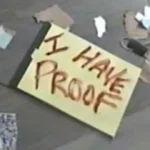 I Have Proof still: a handwritten I HAVE PROOF sign on a cluttered floor, shot on VHS-C
